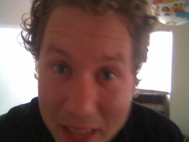 A blurry photo of somebody with curly brownish hair.
He appears to be in the process of smiling but the photo was timed poorly so his emotional state is rather ambiguous.
