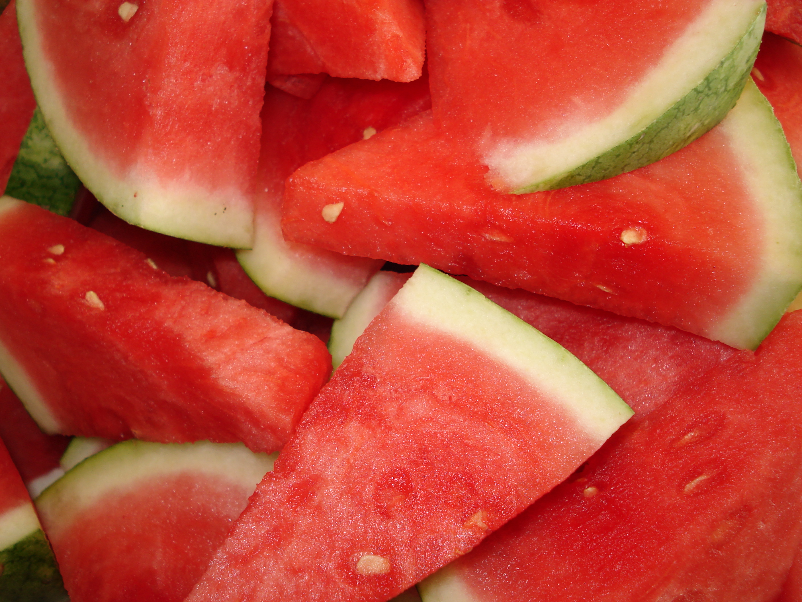 A whole bunch of watermelon slices are piled atop one another.