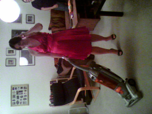 Erin, with nice dress and pearls, vacuuming