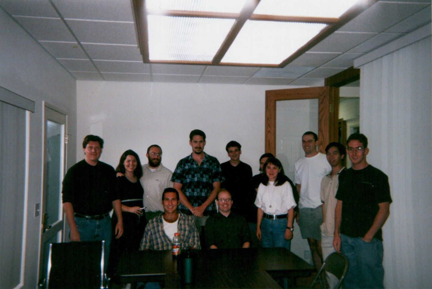 A dozen people pose for a photo in a company’s conference room.