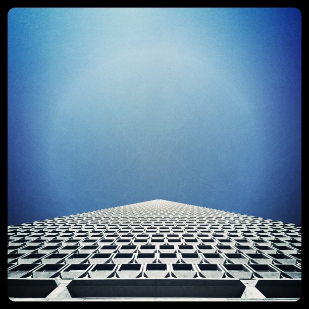 One side of the Transamerica Tower in San Francisco, taken from ground level. The building comes to a single point in the lower center of the photo. The photo is mostly sky.