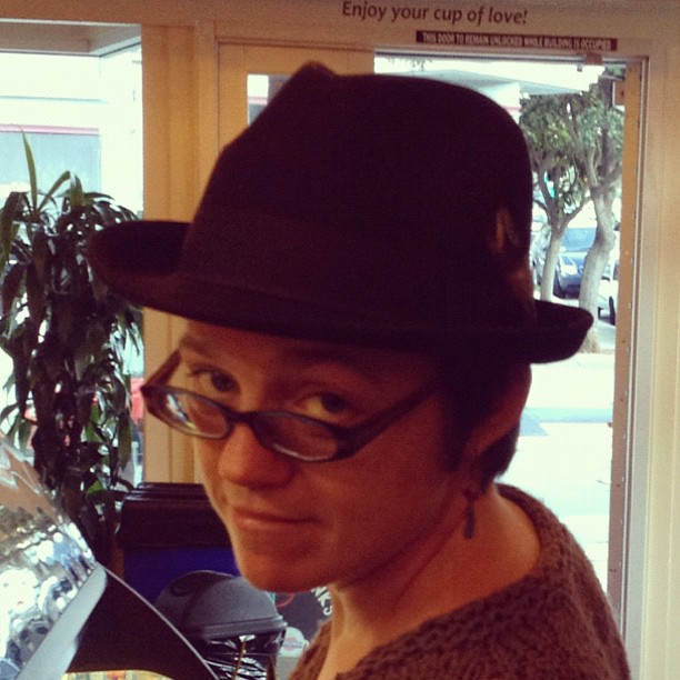 Erin is wearing a dark, old-timey men’s hat.