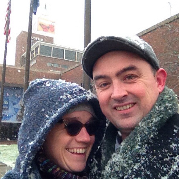 Erin and I are outside. It’s snowing. We’re both bundled up. The Boston Museum of Science is visible behind us.