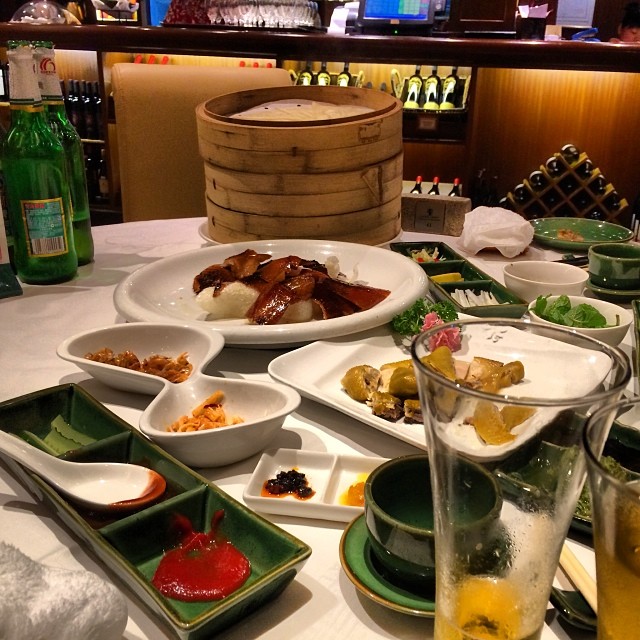 A dinner table at a restaurant is cluttered with many plates of various shapes, sizes, and colors.