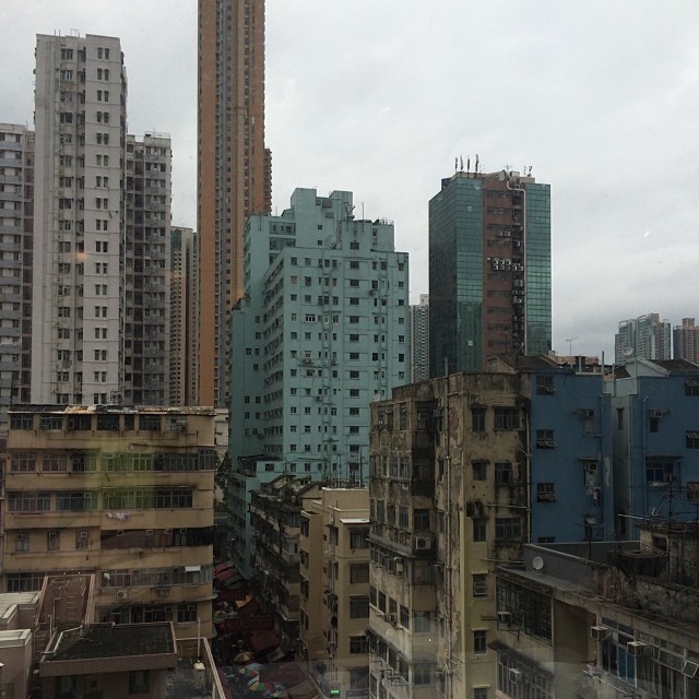 A bunch of dilapidated skyscrapers reach for a cloudy sky.