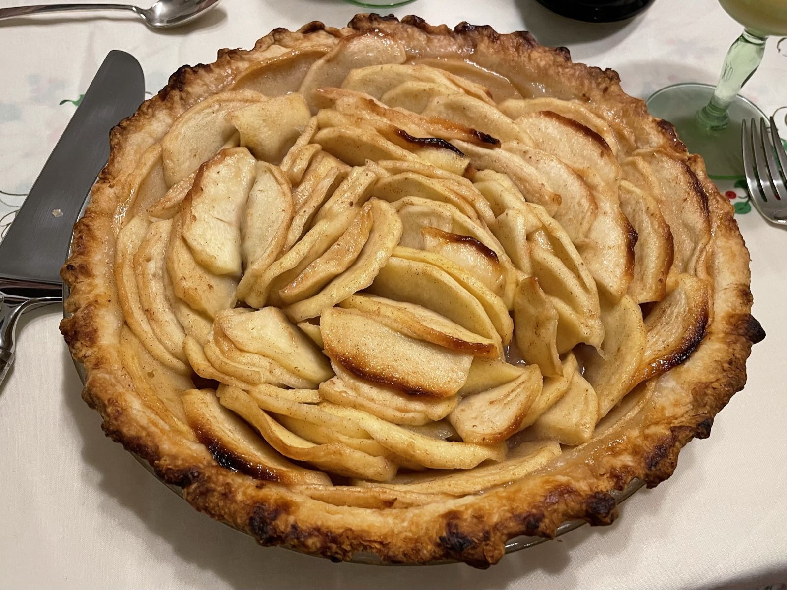An apple pie is sitting on a table. There’s no top crust, putting the delicately sliced apple filling in full view.