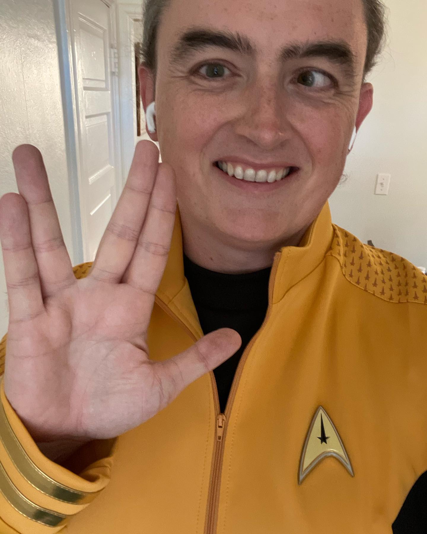 Yours truly, smiling and flashing a Vulcan salute with my right hand. I’m wearing a gold-colored Star Trek uniform.