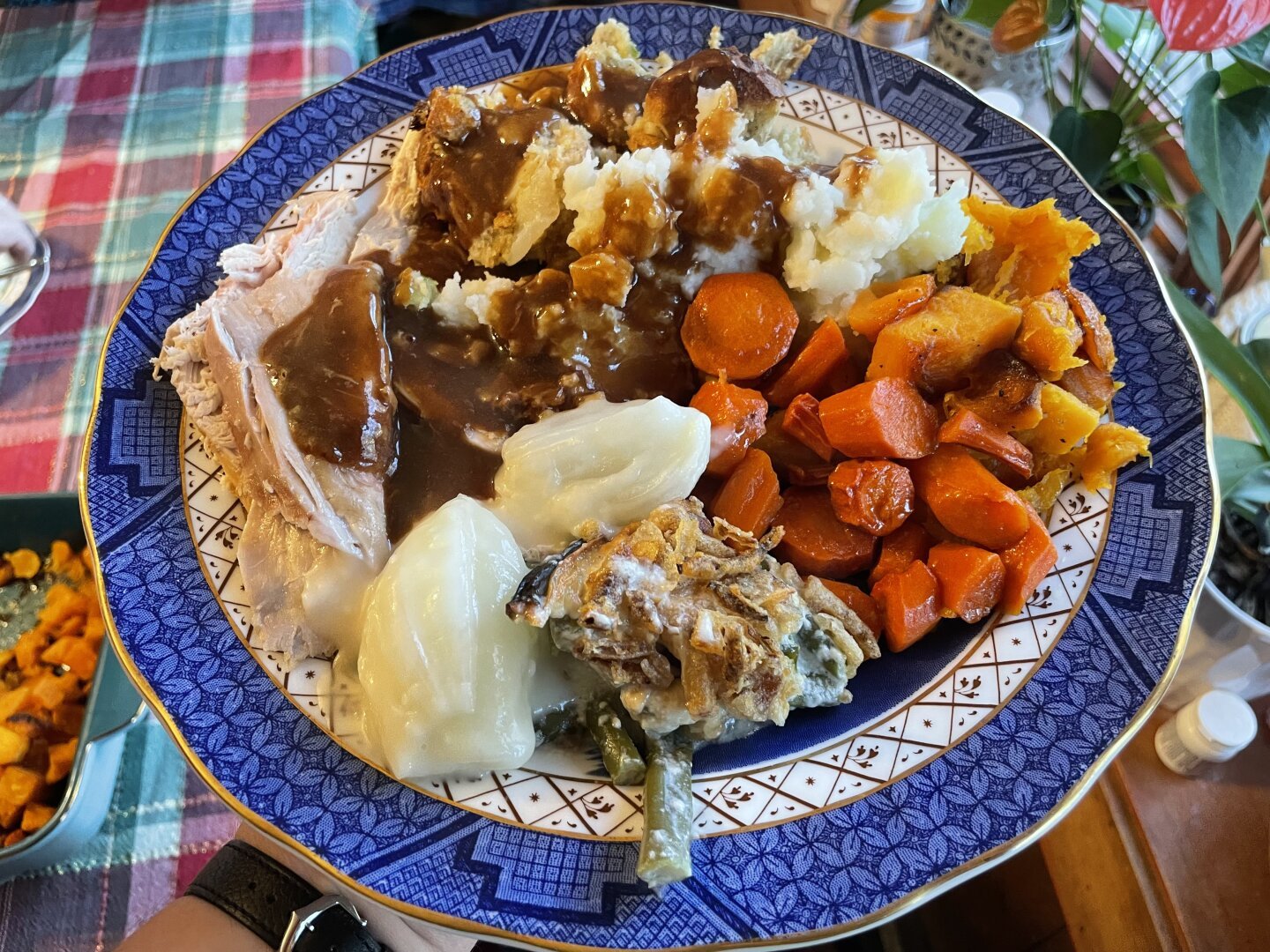dinner plate completely covered in a traditional American thanksgiving dinner spread: turkey, gravy, stuffing, mashed potatoes, etc.