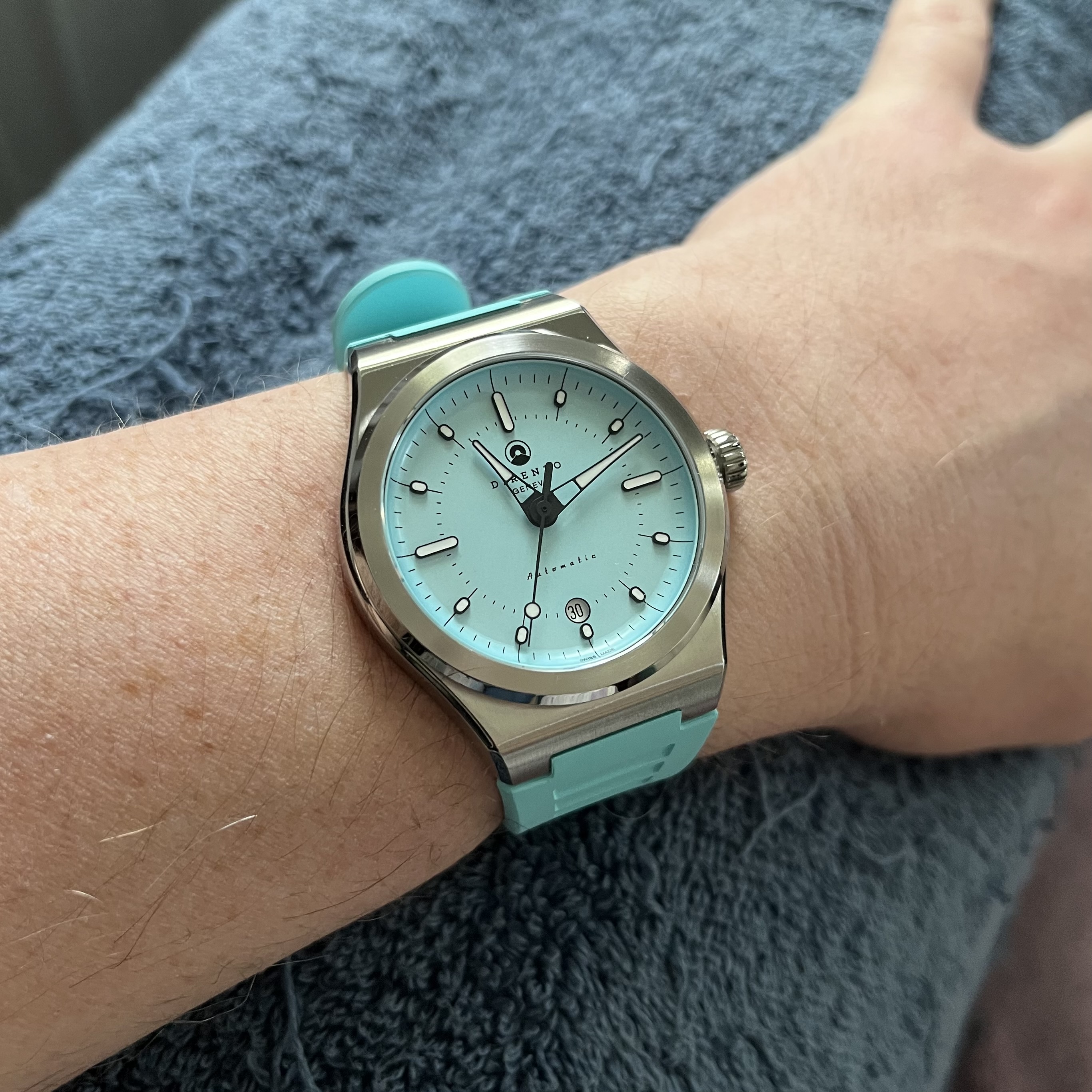 This is a photo of the same watch in the previous photo, but it's on a light blue rubber strap that matches the dial color.