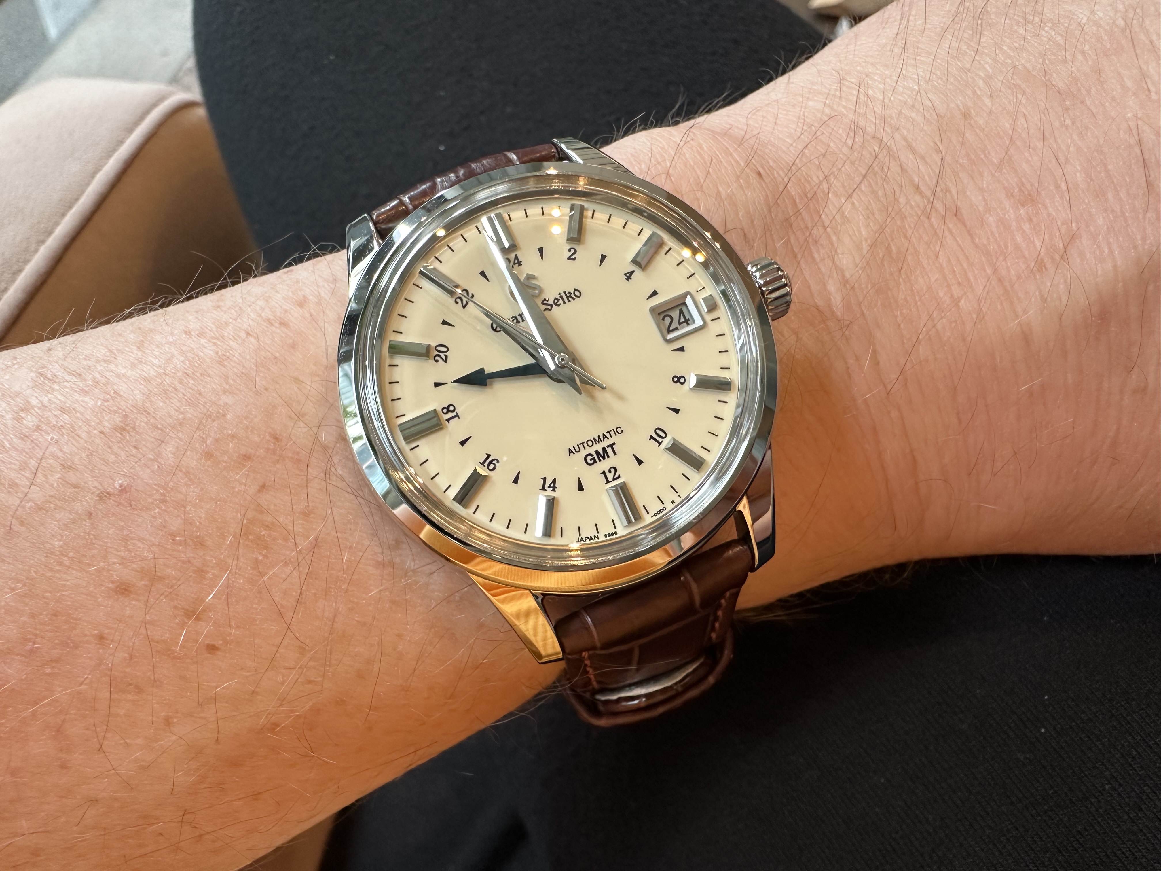 A Grand Seiko SBGM221 Automatic GMT watch on a brown alligator leather strap.
