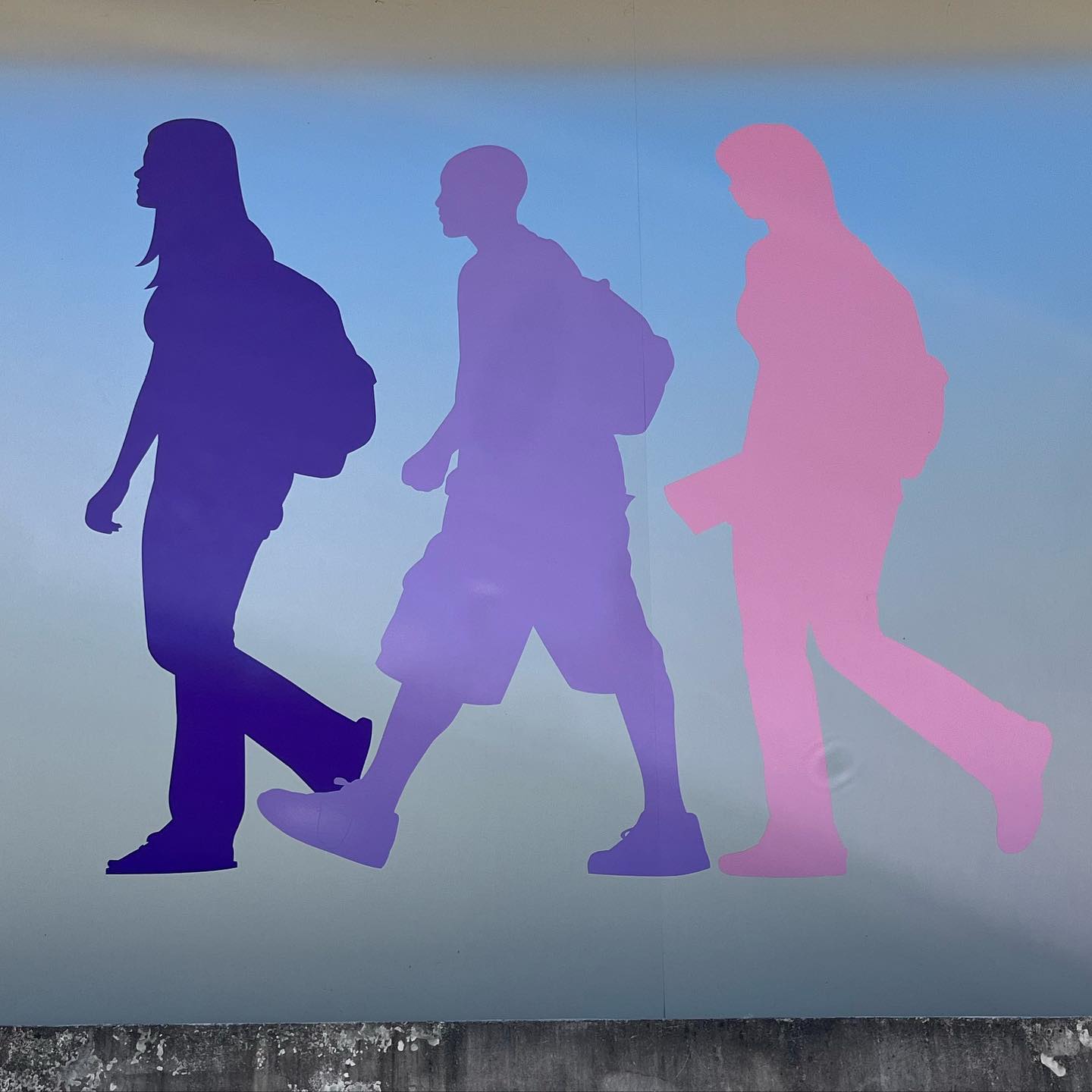 An abstract depiction of three walking school children. One is purple, one lavender, and one pink.