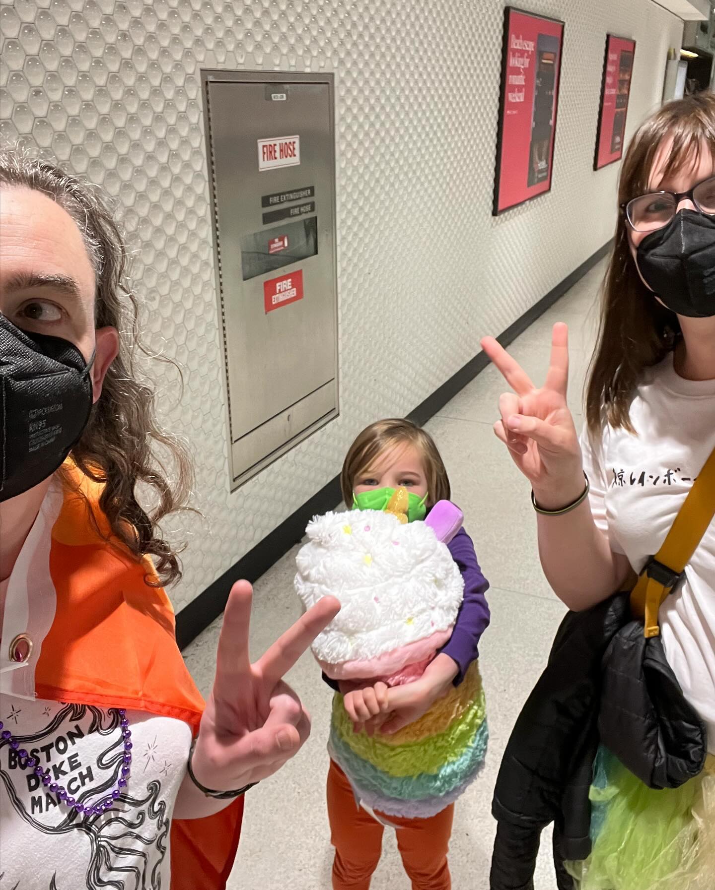 EJ, Eryn, and I take a selfie inside a Muni Metro station.
EJ is hugging a large, colorful stuffie of a cup of boba tea.
I have a rainbow flag draped over my shoulders.
Eryn is wearing a rainbow tutu.