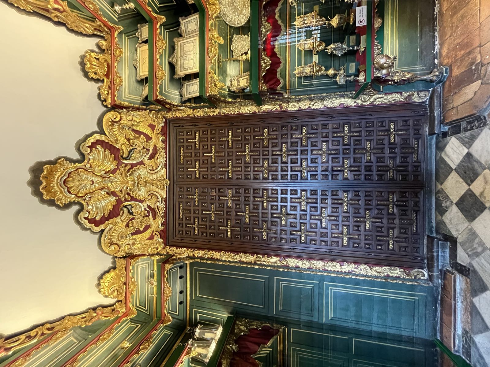 An ornate door surrounded by baroque details in gold.