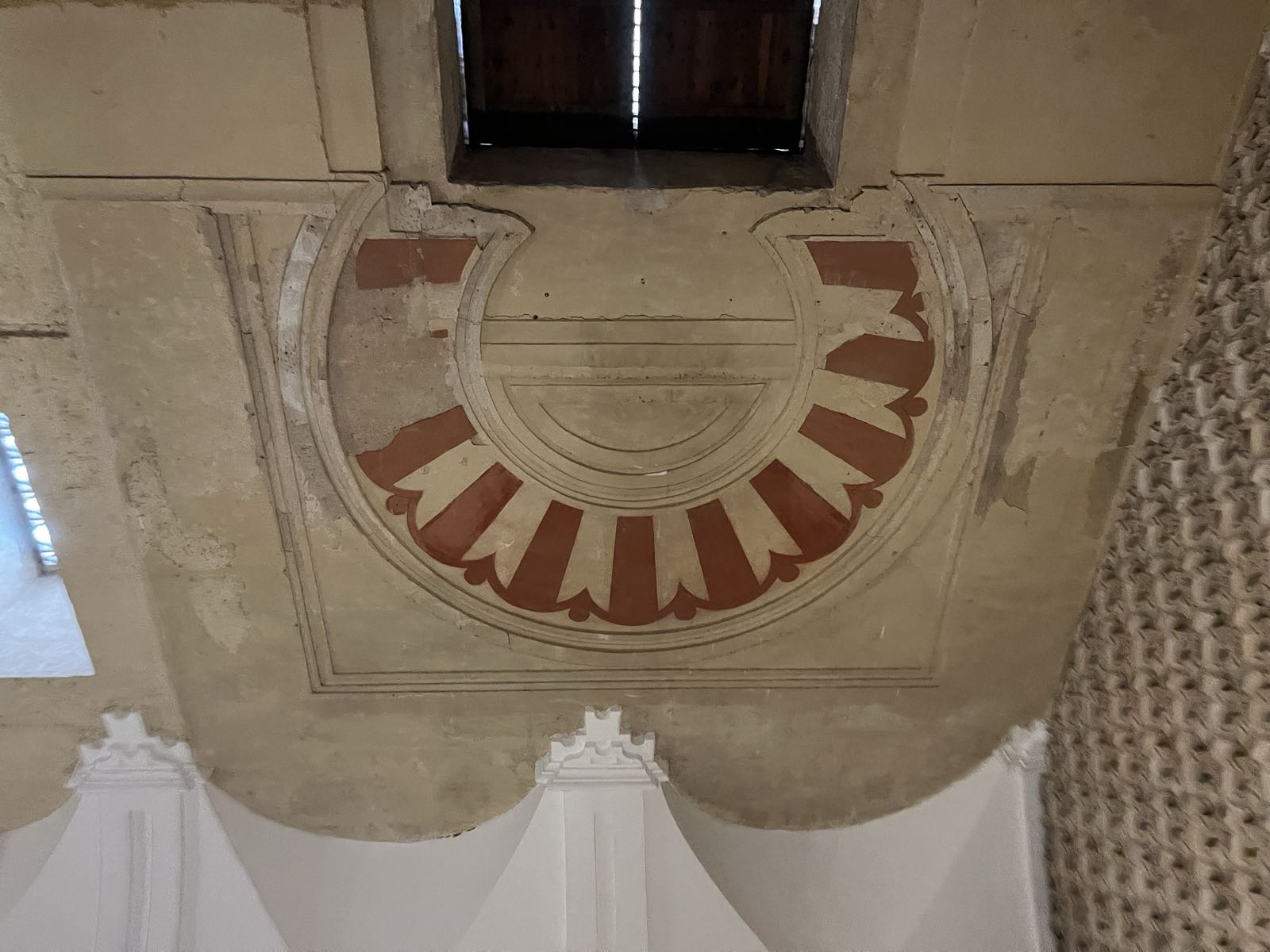 A single red-and-white Moorish arch embedded in the wall above a door in the Capilla Real.