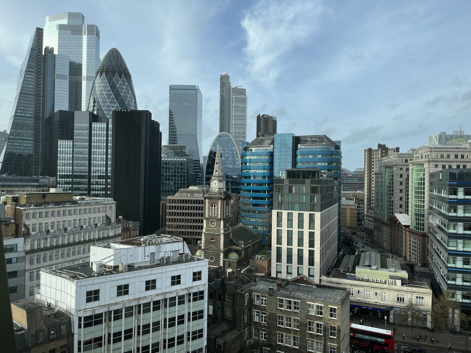 A city skyline.
There’s a clump of modern-looking skyscrapers to the left,
and at center is a church with a tall steeple.
