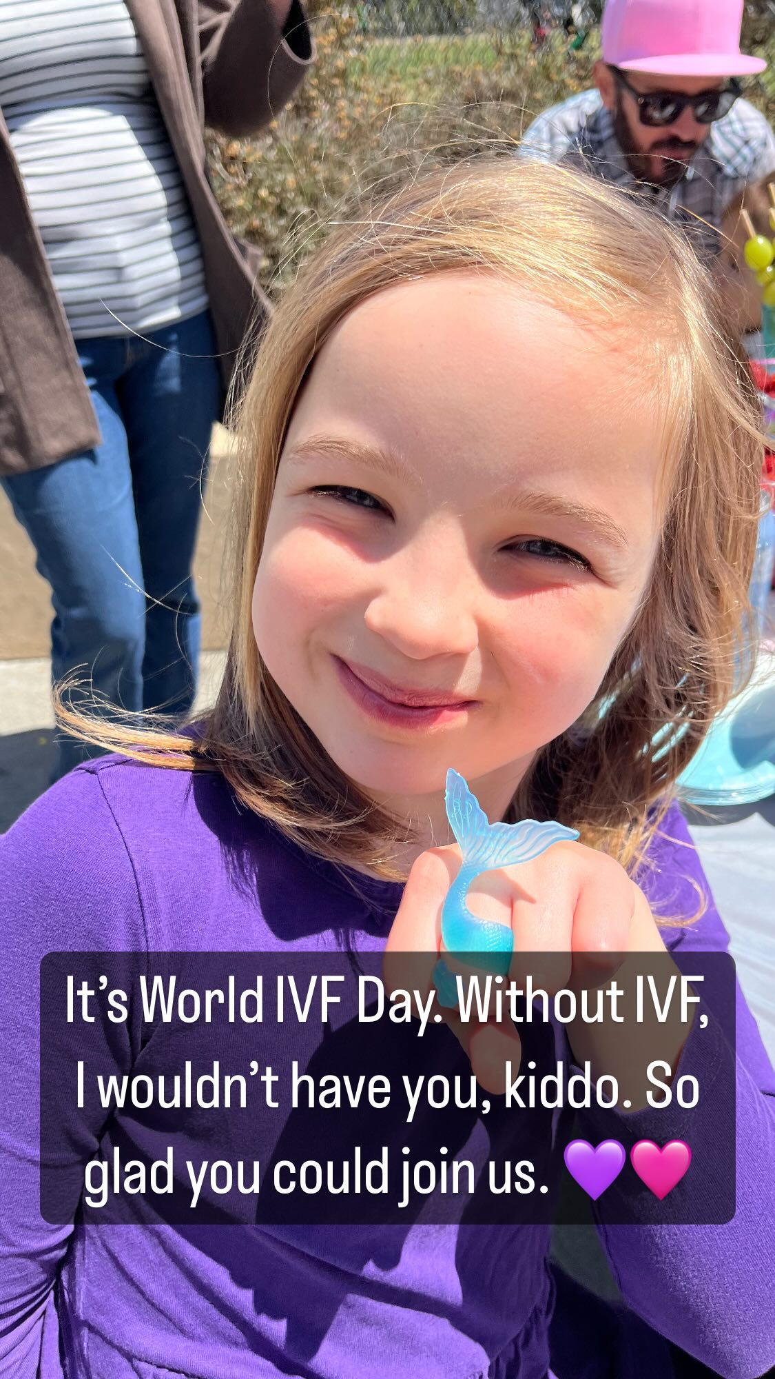 A smiling child wears a blue mermaid-tail ring on one finger.
Superimposed on the image are the words “It’s World IVF Day. Without IVF, I wouldn’t have you, kiddo. So glad you could join us. 💜🩷”