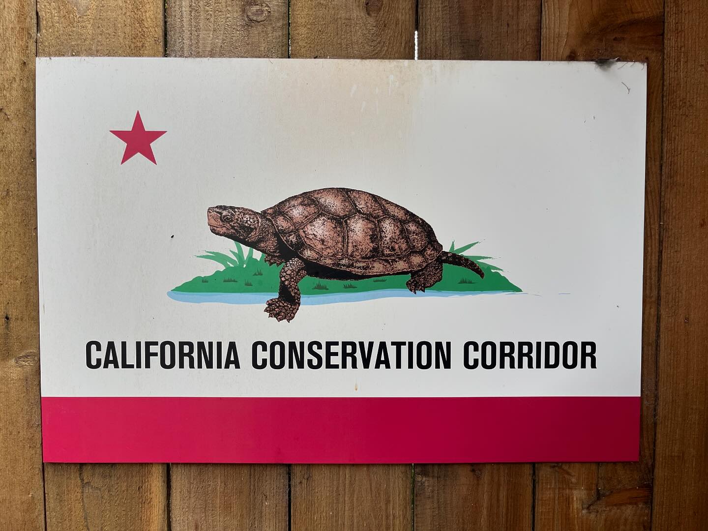 A California flag has been modified. The bear has been replaced by a turtle or tortoise, and the words “California Republic” have been replaced with “California Conservation Corridor.”