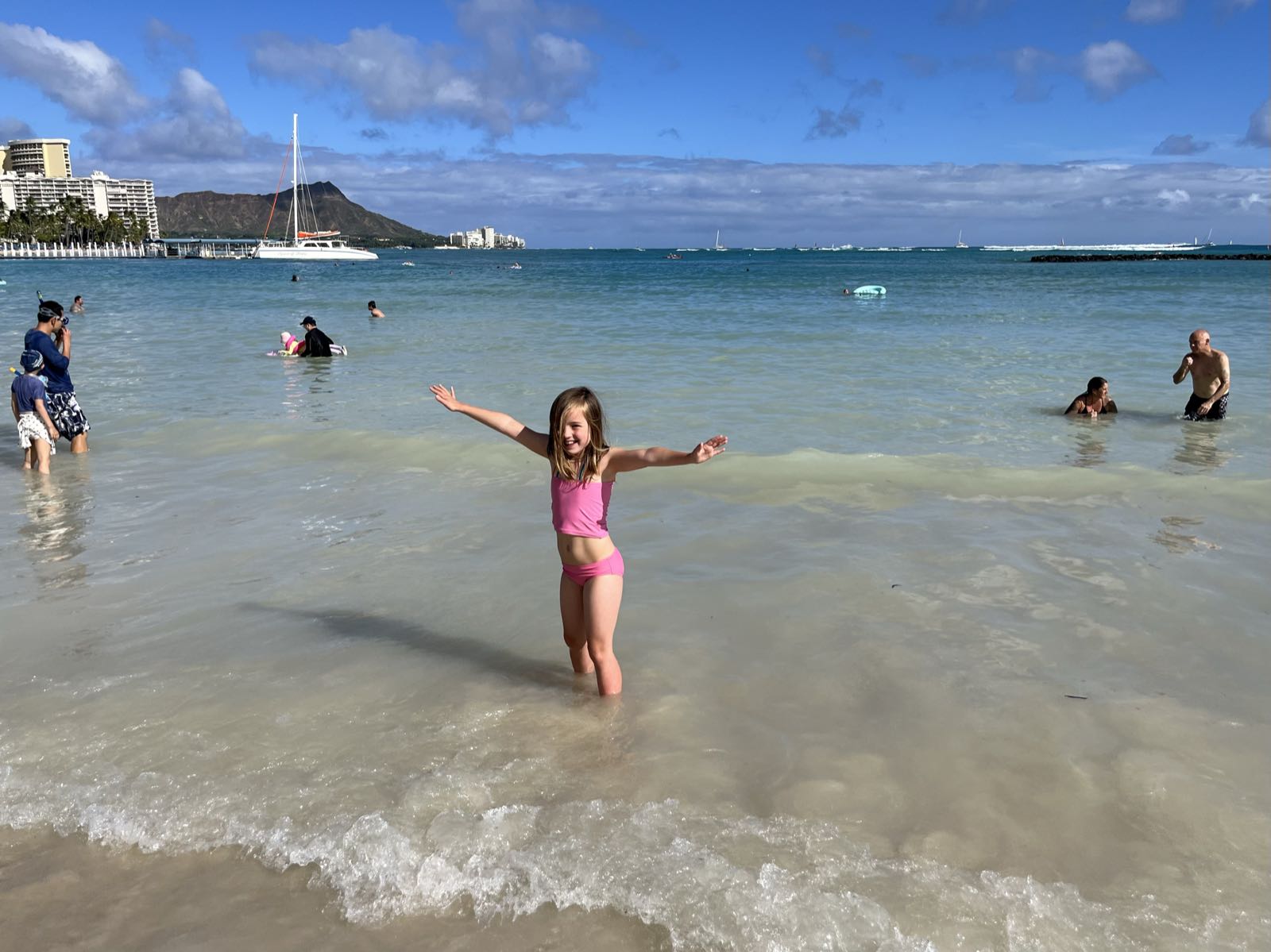 Erin, smiling, with arms outstretched, in the water at Duke Kahanamoku Beach.