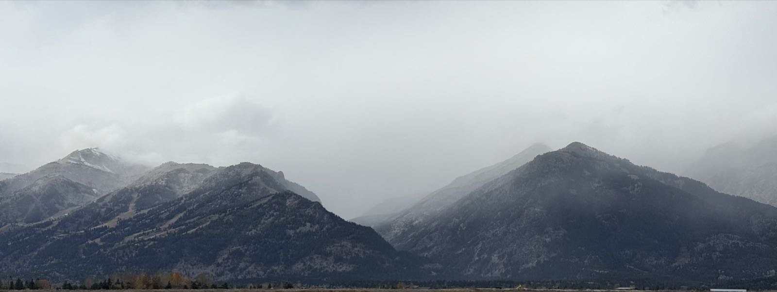 Several wooded mountains stand under a gray, cloudy sky.
