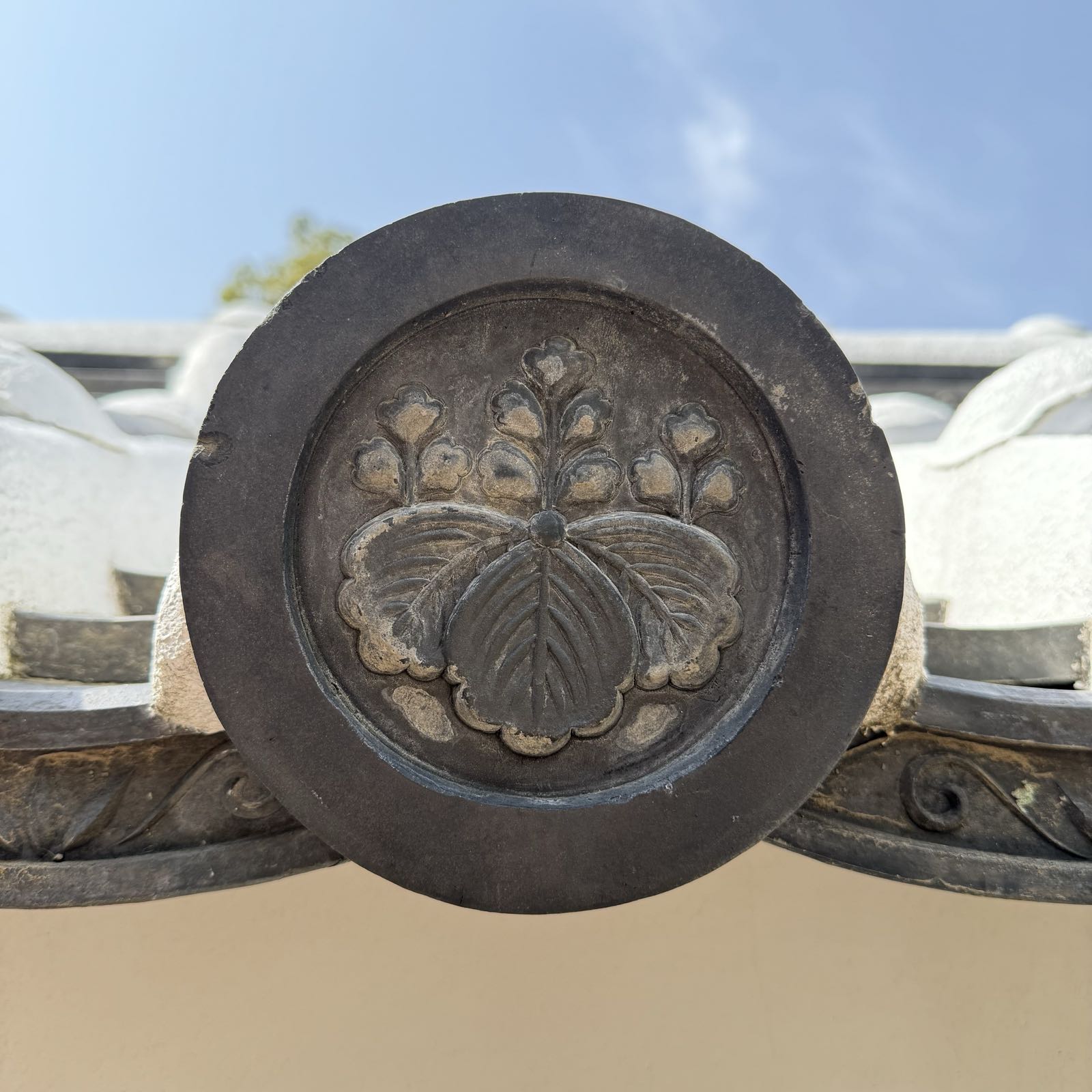 A circular piece of metal has a butterfly or moth rendered in its center.