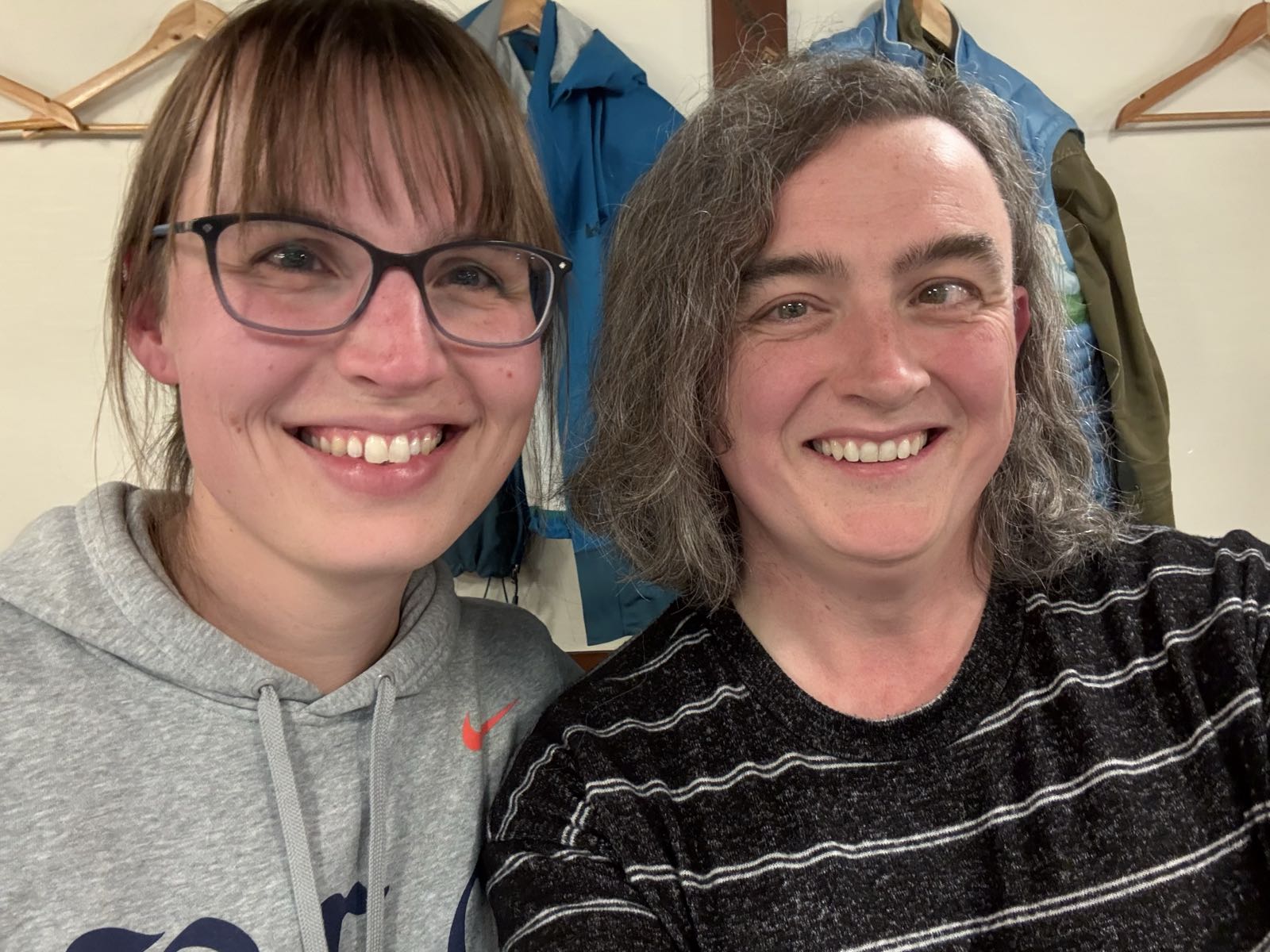 Two women sit close together and are smiling at the camera.