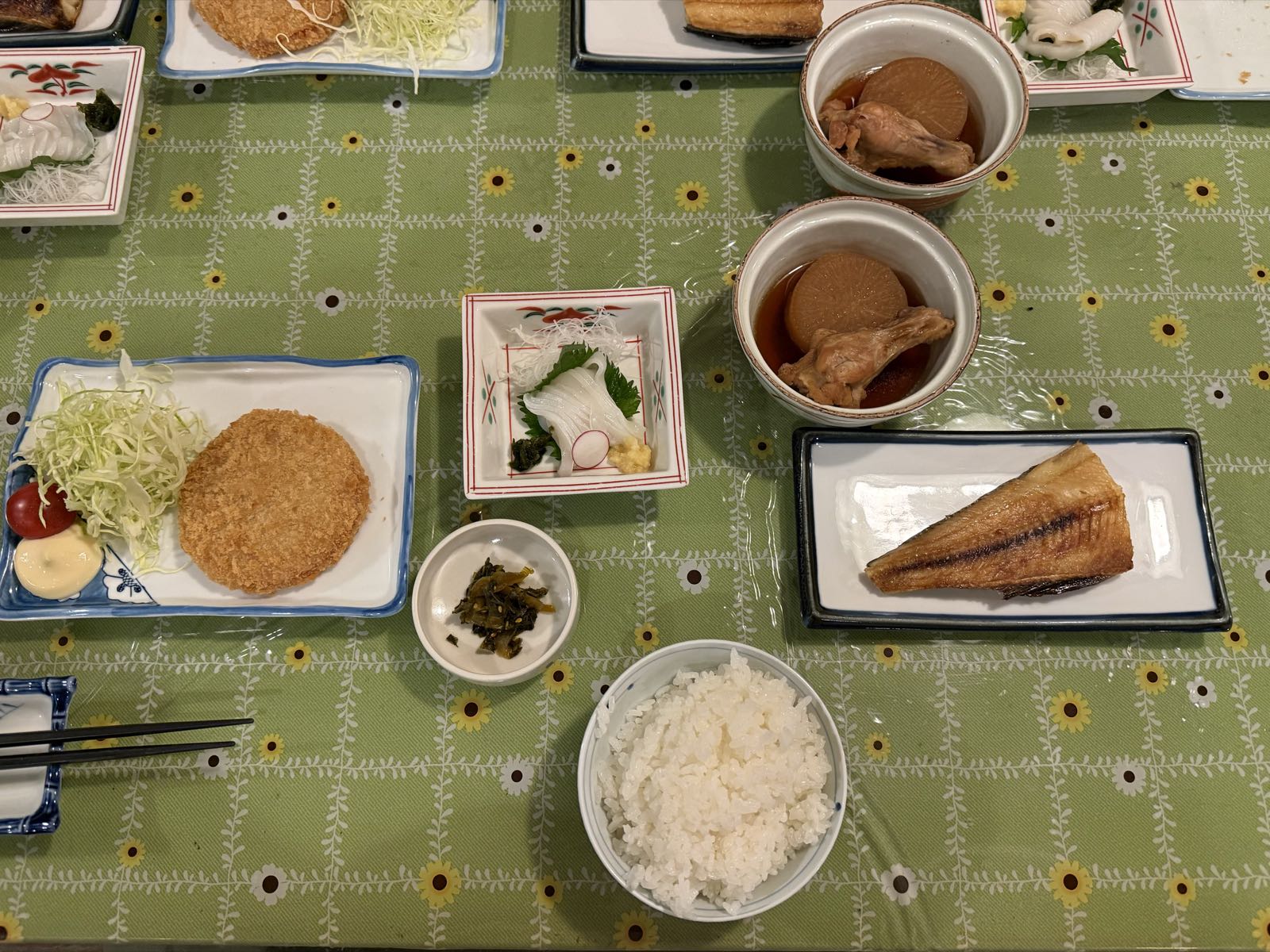 Several small plates of food sit on a table with a green tablecloth.