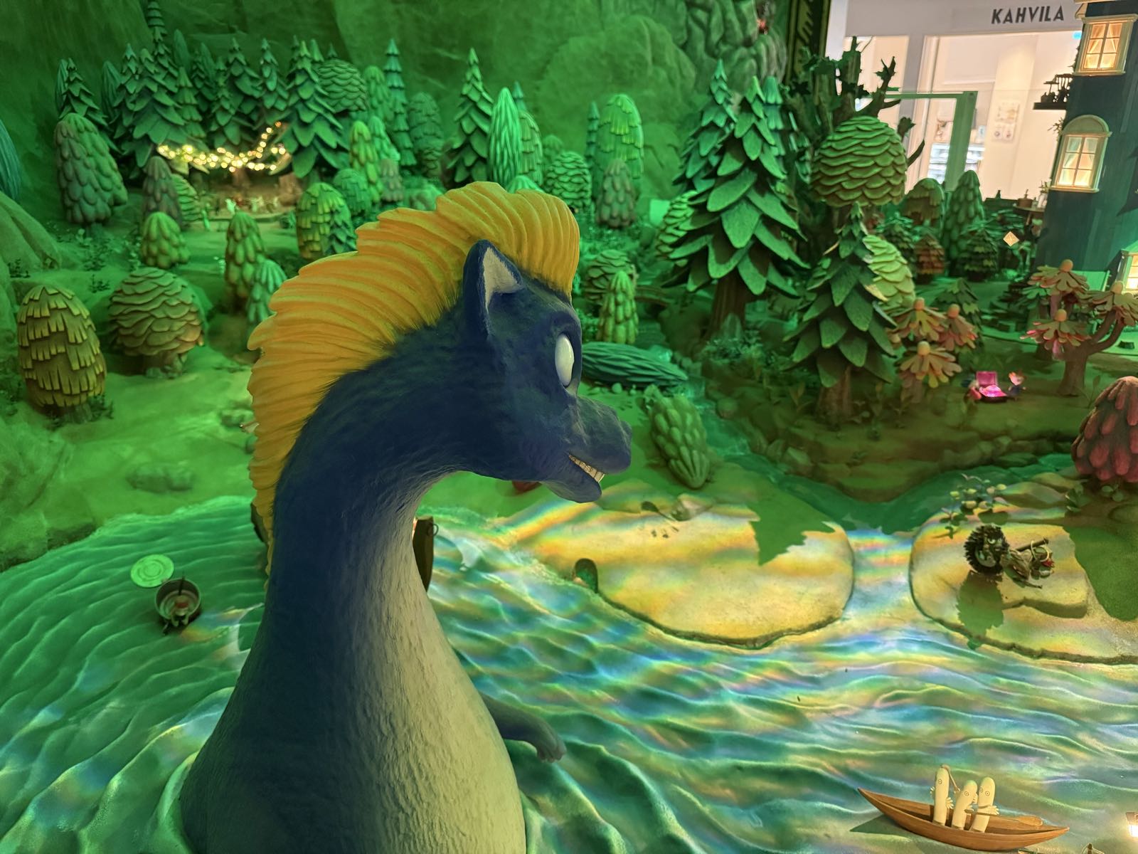 A large, blue Loch Ness Monster-or-maybe-Brontosaurus-looking monster with a yellow mohawk stands in front of a wooded river valley.