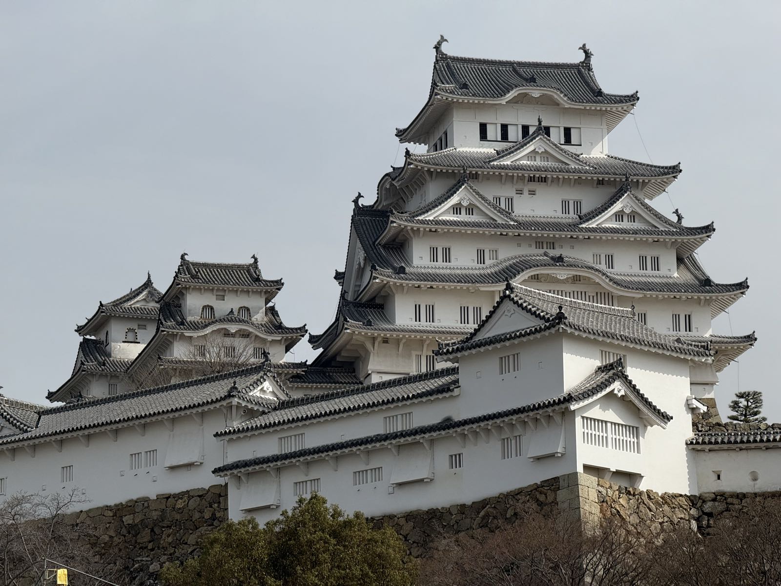 A large white Japanese castle stands on its fortified base. The main keep is at least five storeys tall.