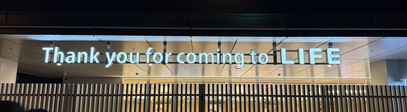 An illuminated sign on the side of a building reads “Thank you for coming to LIFE”.