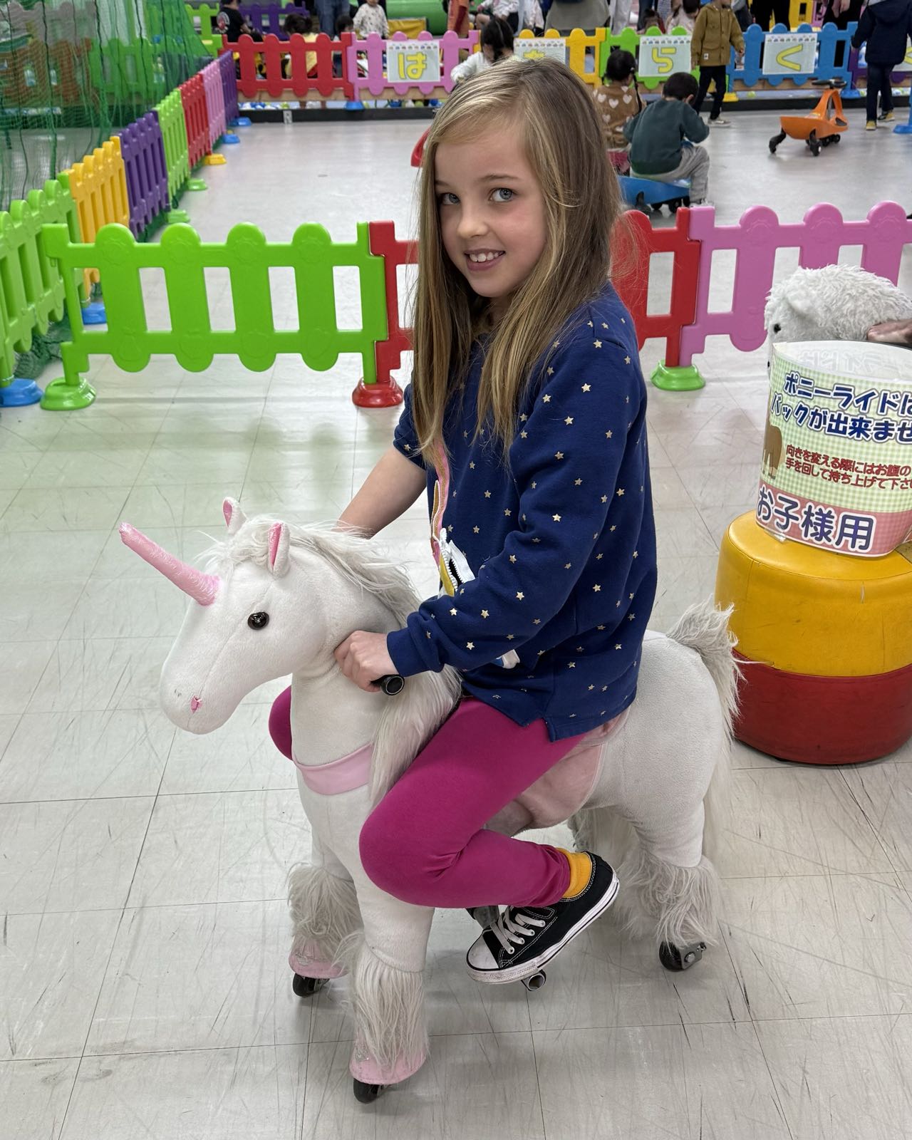 A child sits on a large unicorn riding toy.
