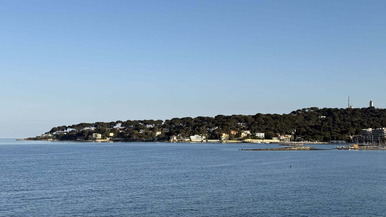 A wooded peninsula separates the sea from a clear sky.
