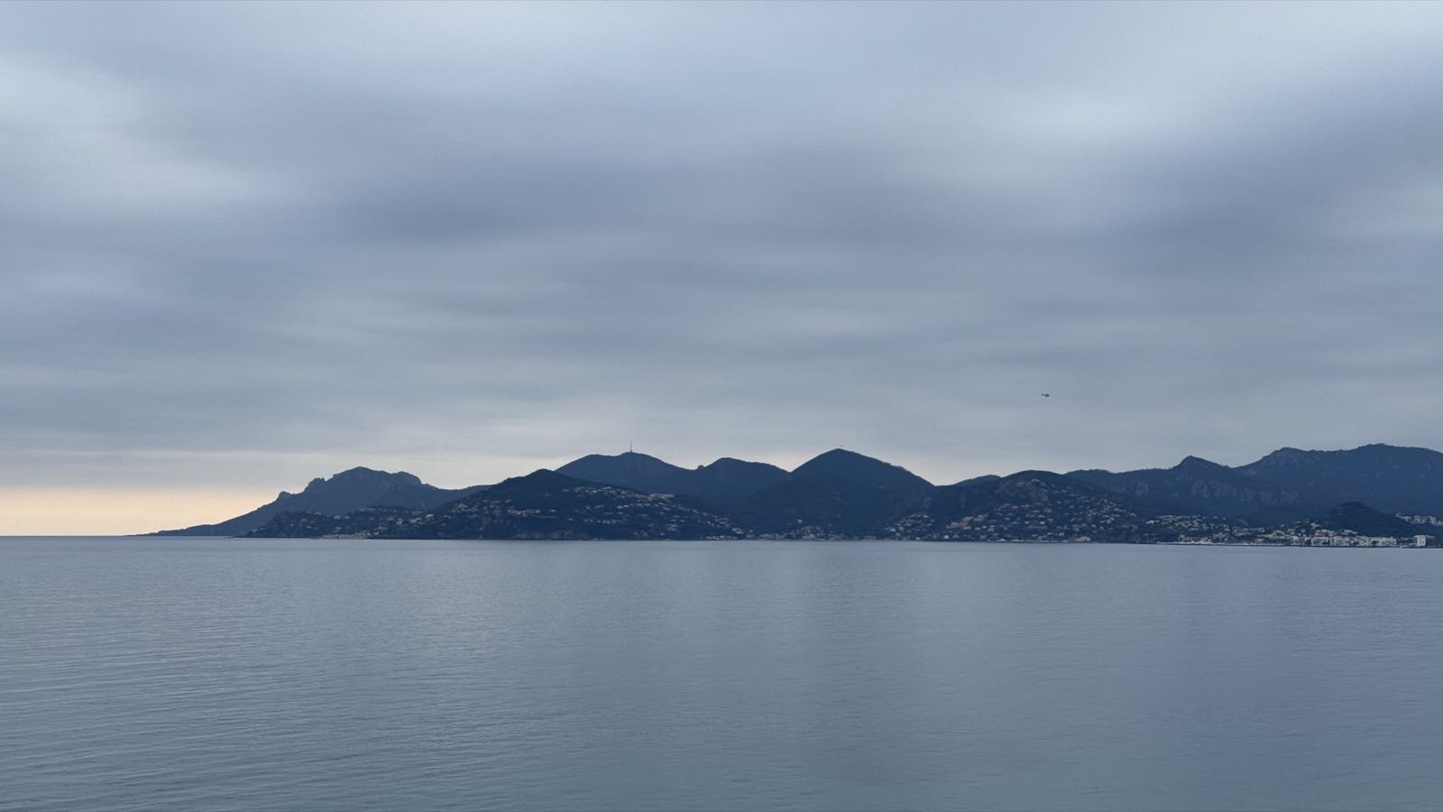 A mountainous peninsula separates a cloudy sky from the sea.