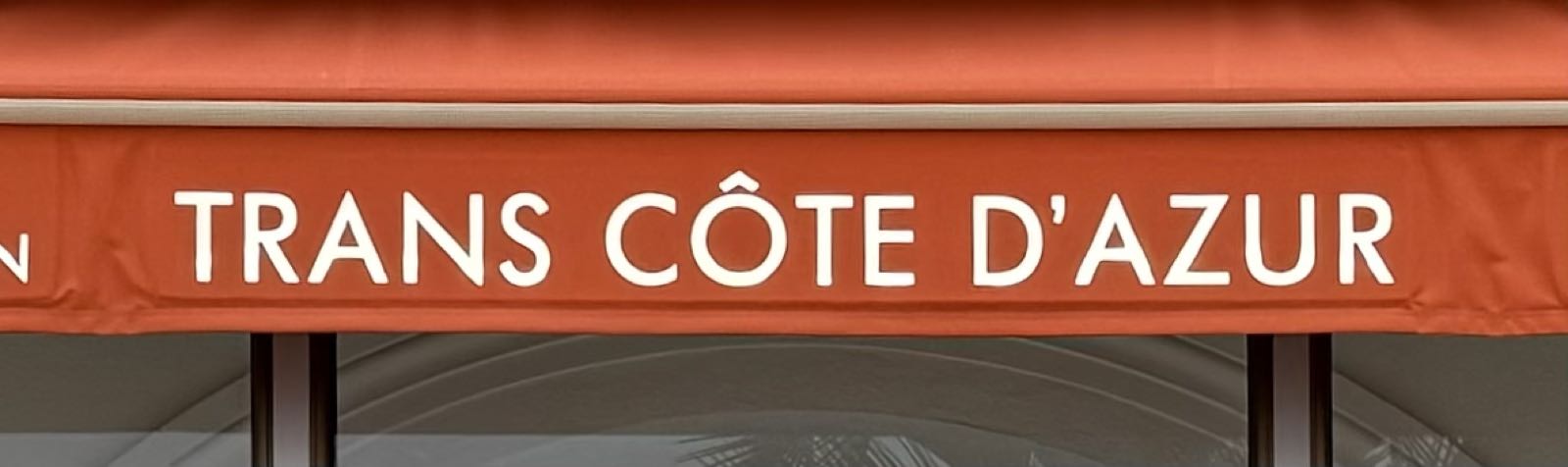 An orange awning has white text that reads « Trans Côte d’Azur ».
