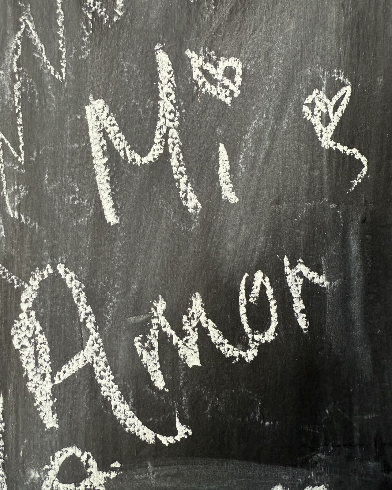 A close-up of some text on a chalkboard. The text reads “mi amor”. The dot of the lower case “i” is heart shaped.