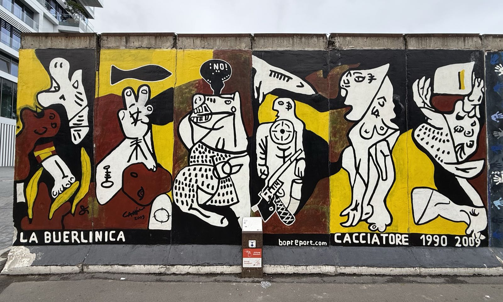 A painting in black, marroon, yellow, and white depicts a number of people in various states of distress.