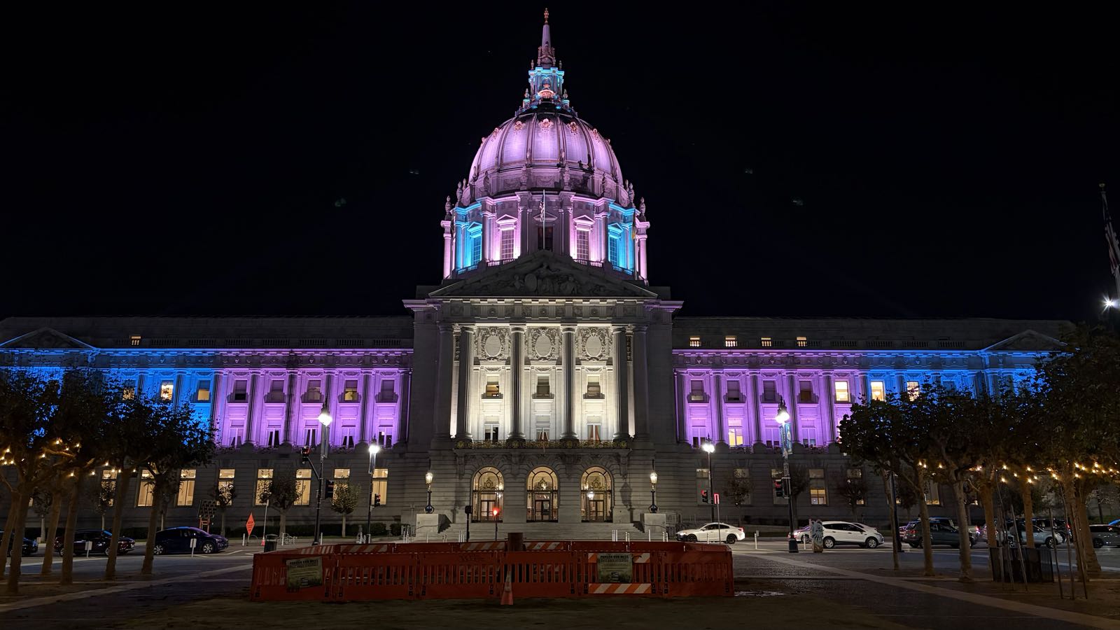 San Francisco City Hall, a domed neoclassical building, is lit up in the colors of the transgender pride flag.