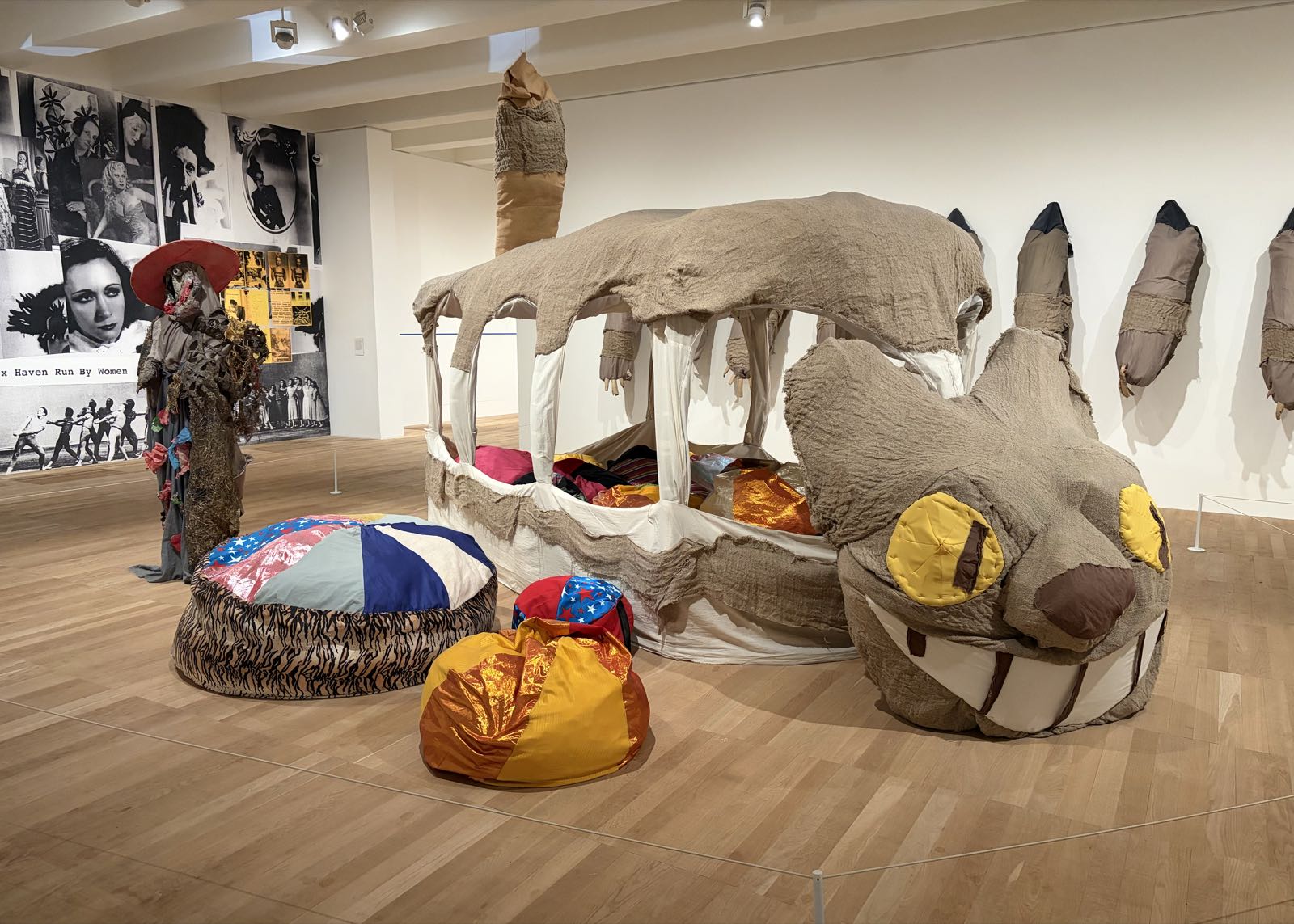 A real-life recreation of Hayao Miyazaki’s Catbus (from My Neighbor Totoro) sits on the floor in the middle of a room. On the wall behind it hang each of its legs, which had been removed from the Catbus.