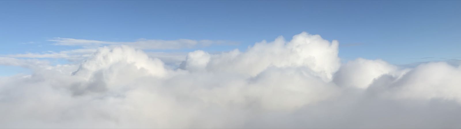 Below a clear blue sky, the view from the camera to the horizon is entirely filled with fluffy white clouds.