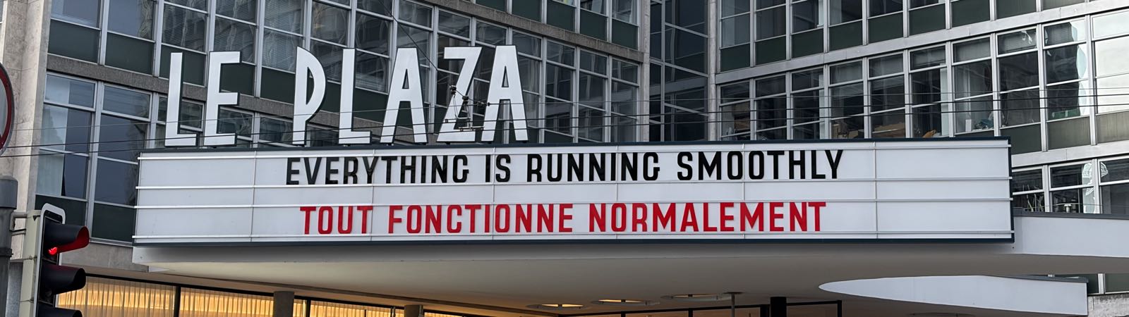 A marquee above the entrance to Le Plaza reads “EVERYTHING IS RUNNING SMOOTHLY” in English and « TOUT FONCTIONNE NORMALEMENT » in French.