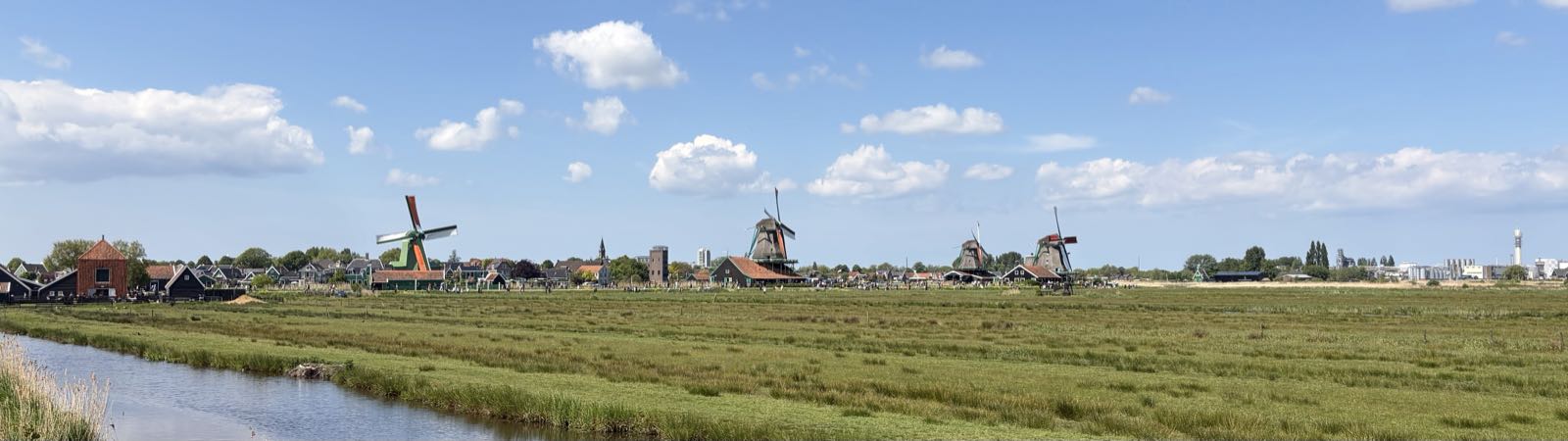 Several windmills stand under a sunny, partly cloudy sky.
