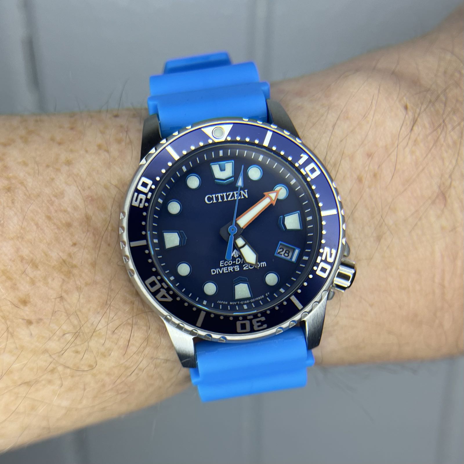 A steel dive watch on a bright blue rubber strap. The dial and bezel are navy blue.
