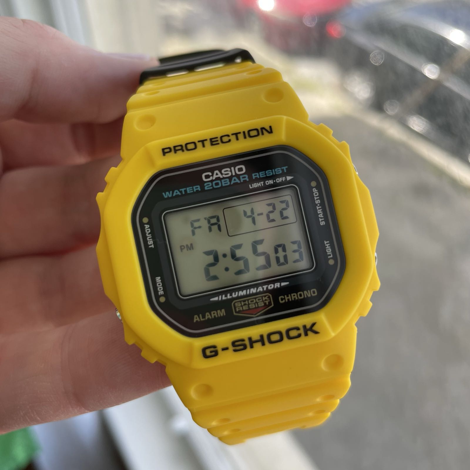 A yellow plastic digital watch with a black dial surrounding a positive display.