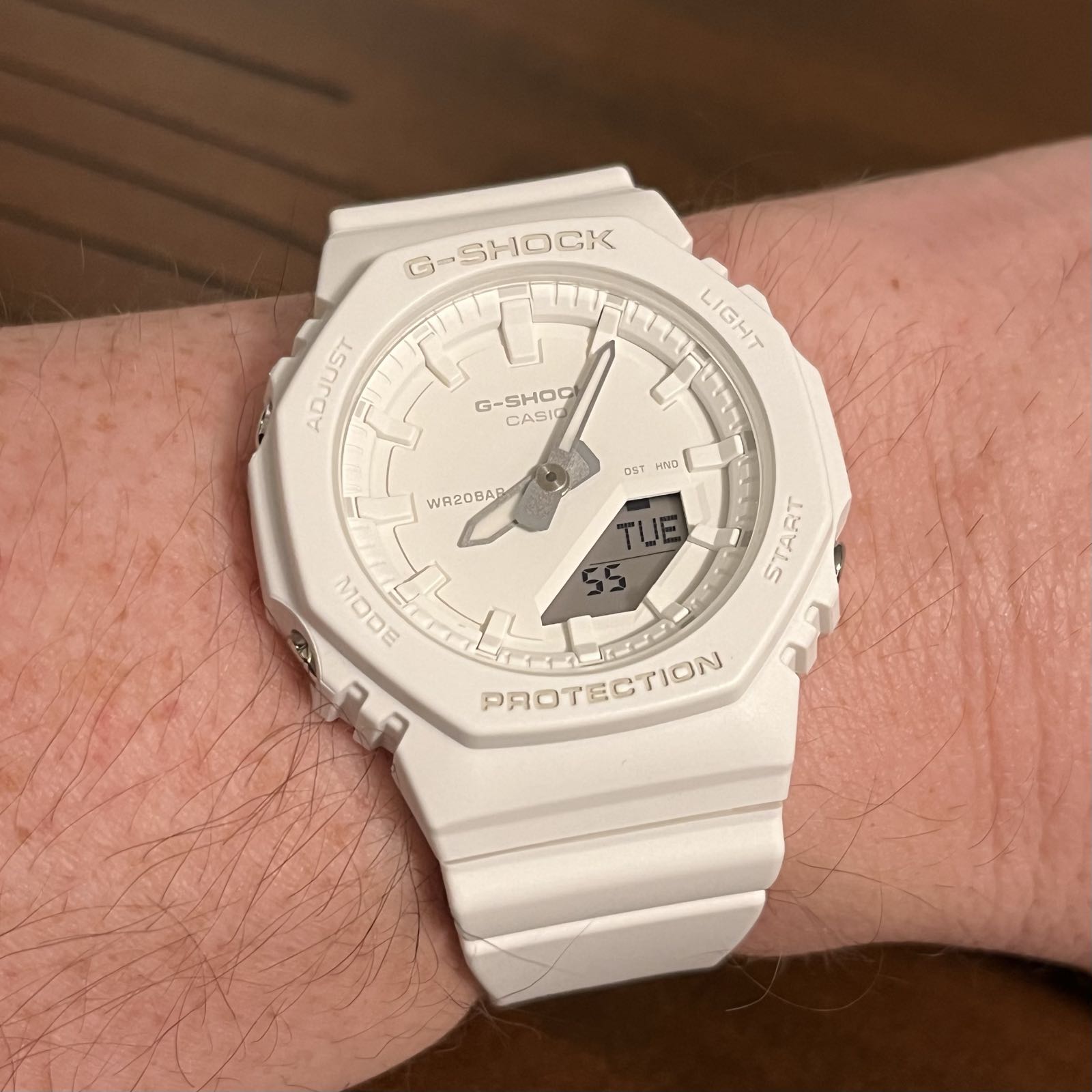 A white plastic analog/digital watch on a matching strap. The dial and indicies are also white, while the hands are silver.