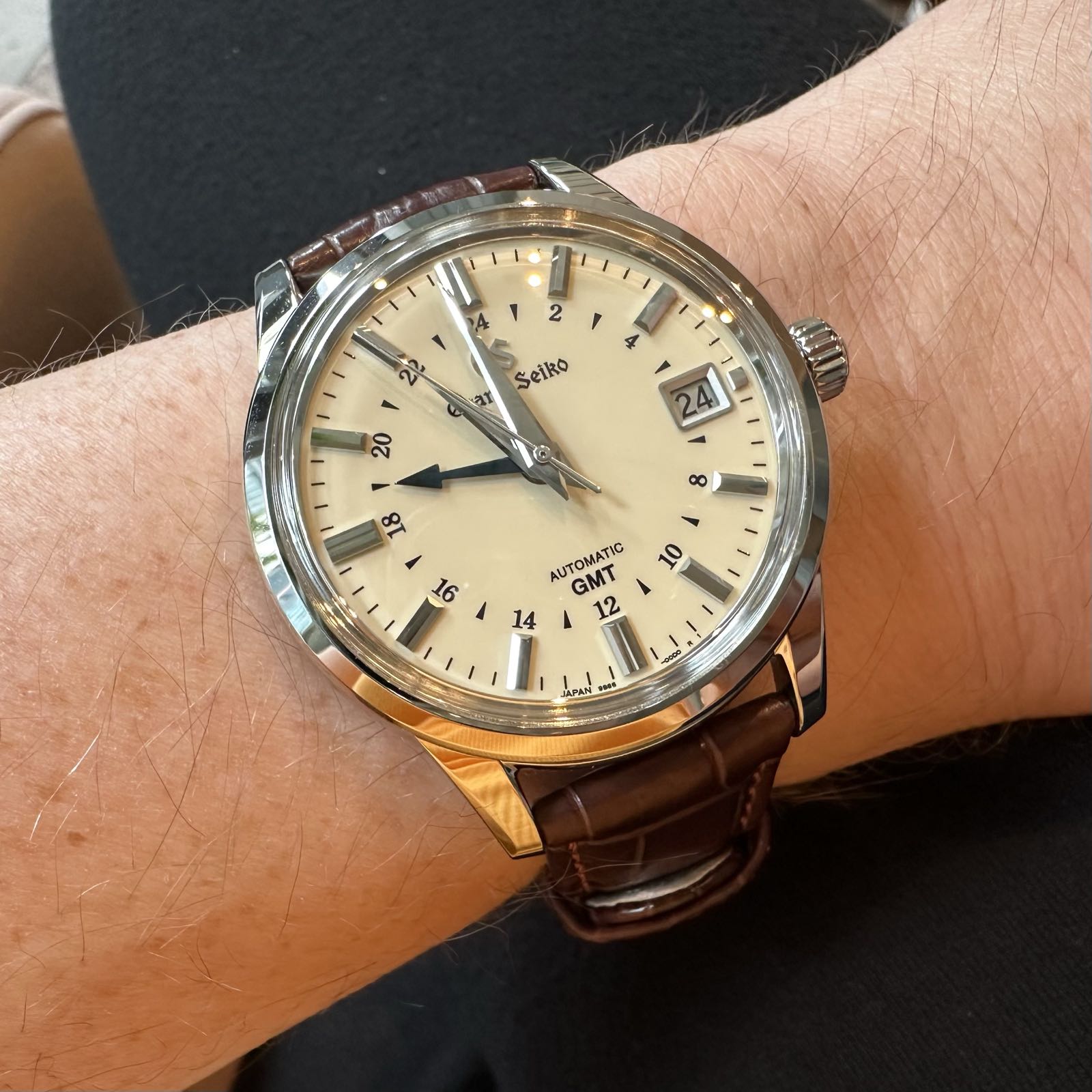 A champagne-dial four-hand dress watch. The case, indicies, and hands are high polish steel. There’s a fourth hand, blued, with an arrow tip, that’s about as long as the hour hand. It points to an inner, 24-hour track. There’s a date complication at 3:00. The watch is on a brown leather strap.