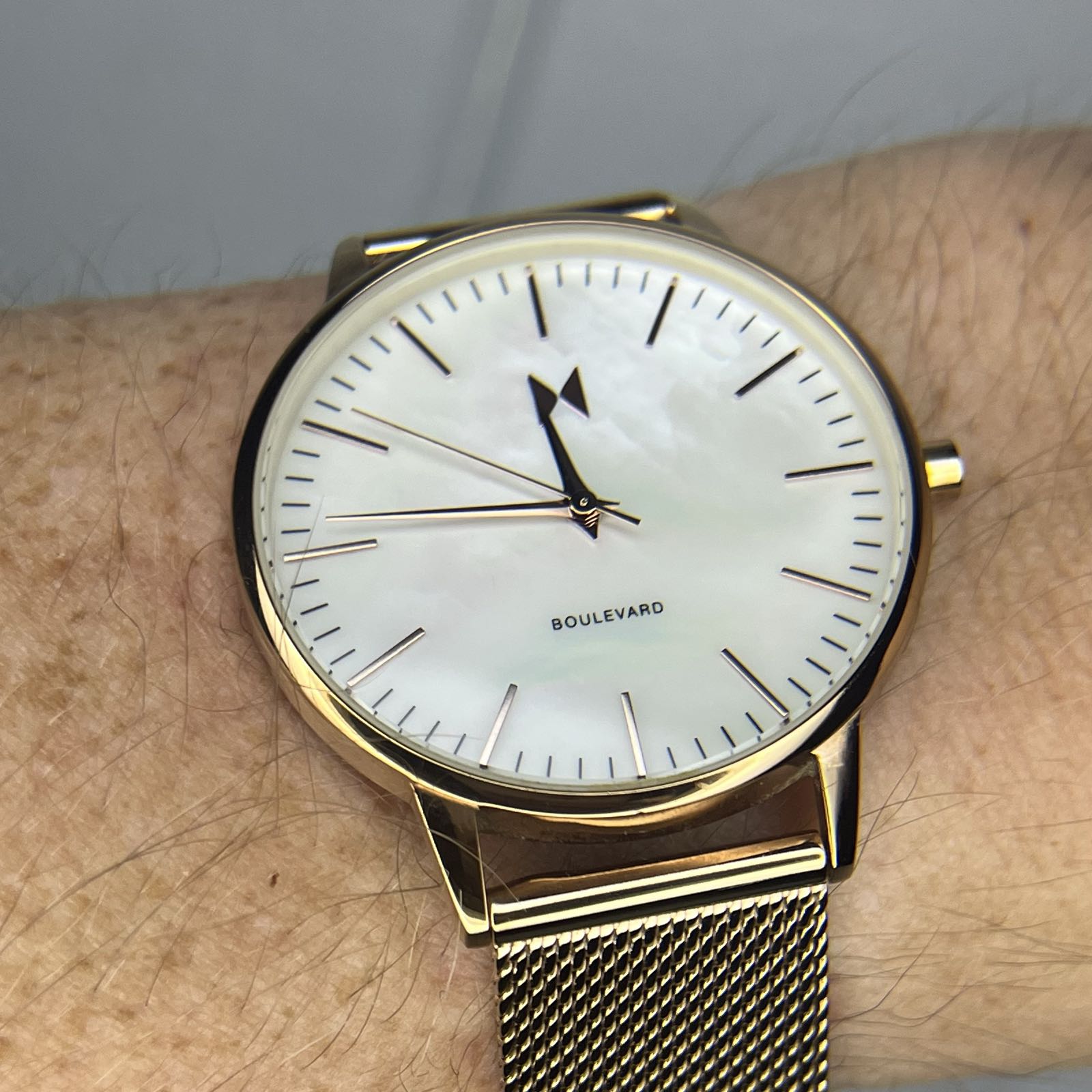 A simple analog dress watch with a mother-of-pearl dial. The case and bracelet are rose gold colored.
