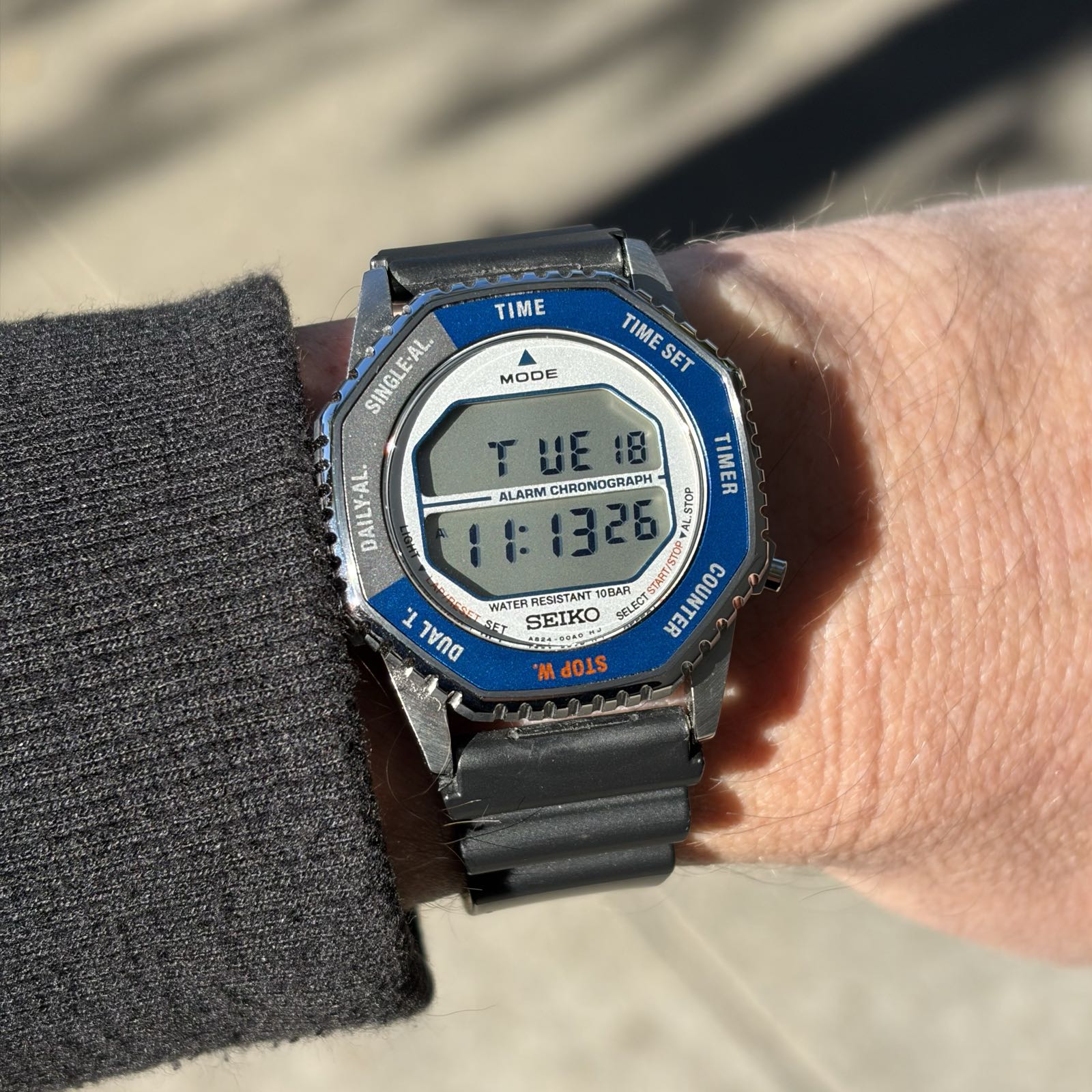A digital watch with a split screen has a blue and gray bezel.