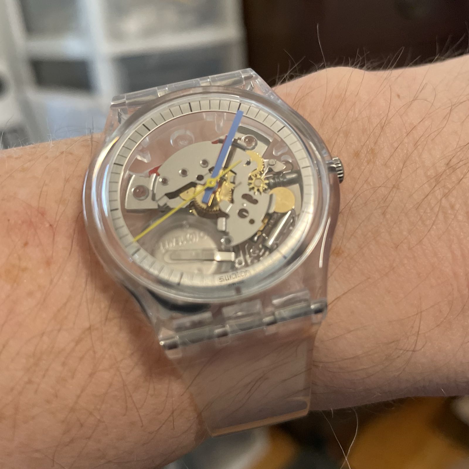 A transparent, ’jelly’ style quartz watch with red, blue, and yellow hands. In addition to the case and strap, the dial is also transparent, so the movement is visible.